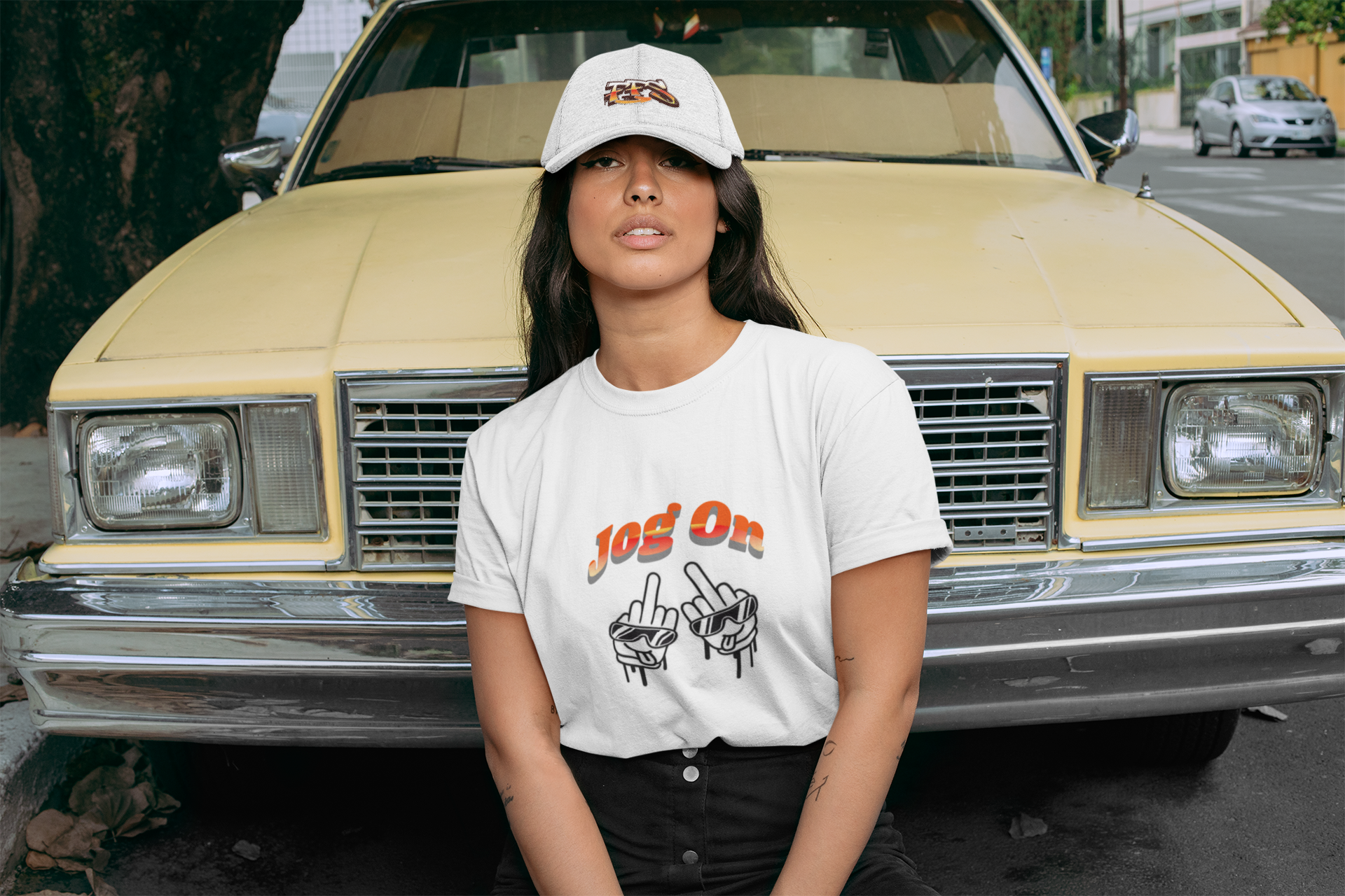 Female wearing a white Jog On graphic t-shirt standing in front of a vintage car.