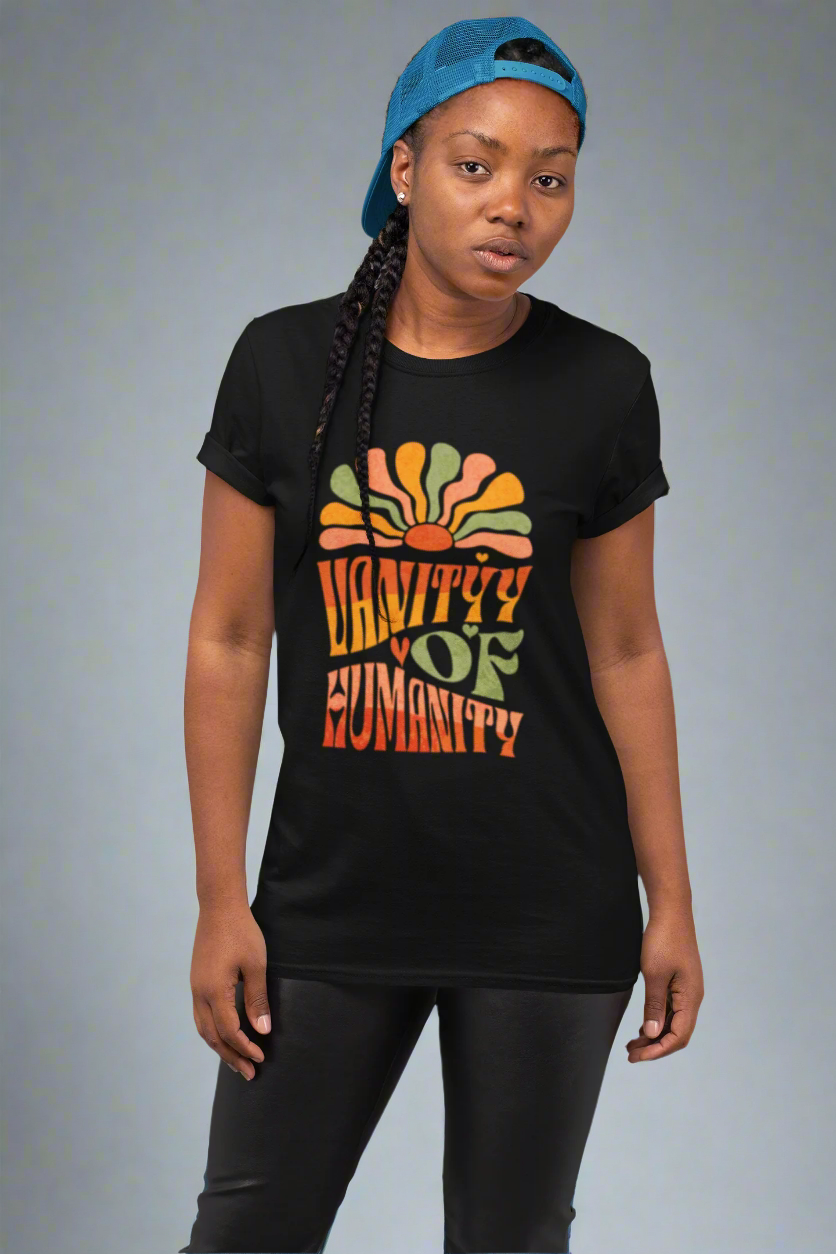 Person wearing a black Vanity of Humanity T-shirt with bold colourful text design on a light purple background