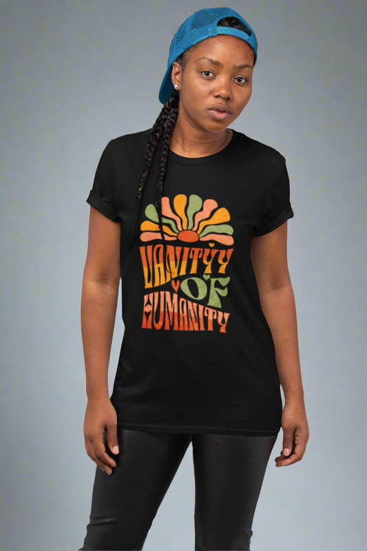 Person wearing a black Vanity of Humanity T-shirt with bold colourful text design on a light purple background